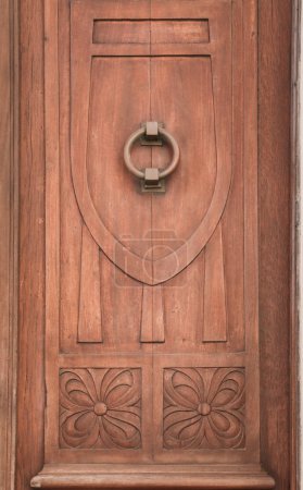 Schöne und alte braune Holztür mit geschnitzten Details und Türklopfer in der Altstadt von Olivenza, Badajoz