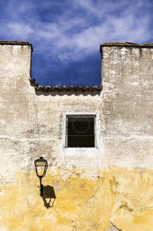 Maison ancienne avec façade déchiquetée colorée et lampadaire à Elvas, Portugal