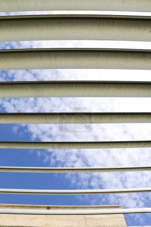 Estructura de vigas de metal blanco y cielo azul y nubes en el fondo