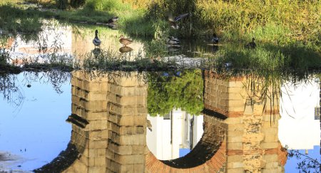 Beautiful Roman Aqueduct of Merida called 'Aqueduct of Miracles' reflected on the Guadiana River with ducks