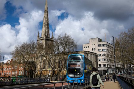Foto de Bristol, Inglaterra 30 de marzo de 2024: Autobús azul típico que cruza el puente de Bristol. Iglesia de San Nicolás en el fondo - Imagen libre de derechos