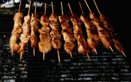 Brochettes de viande marinée grillées sur des charbons chauds, présentant un délicieux extérieur caramélisé aux saveurs fumées.