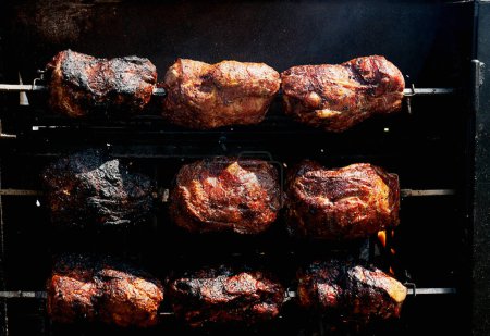 Téléchargez les photos : Découpes multiples de viande sur une grille de rôtisserie, avec des flammes et de la fumée, mettant en évidence le processus de cuisson rustique. - en image libre de droit