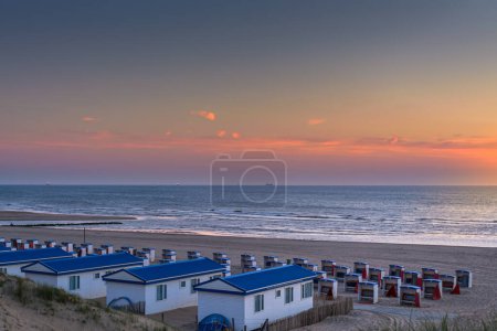 Photo for Katwijk aan Zee, The Netherlands - June 11, 2015: View from the dunes on the beach houses and cabins during sunset in Katwijk - Royalty Free Image