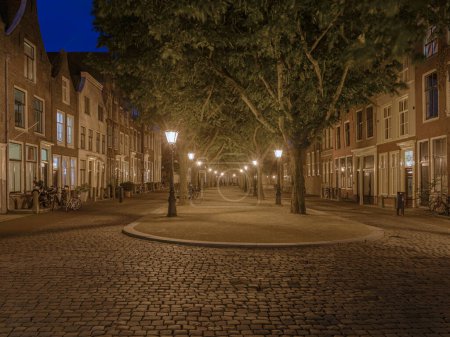 Téléchargez les photos : Leyde, Pays-Bas - 5 septembre 2015 : Un Hooglandse Kerkgracht vide à Leyde dans la soirée. La voie bien connue avec des arbres est magnifiquement éclairée la nuit par des lampadaires entre chaque arbre - en image libre de droit