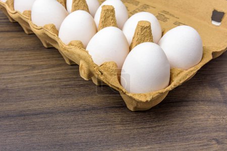 Téléchargez les photos : Gros plan d'œufs en liberté dans un carton d'œufs en carton sur une table en noyer foncé - en image libre de droit