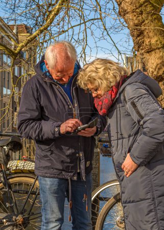 Foto de Utrecht, Países Bajos - 24 de febrero de 2018: Una pareja de ancianos mirando desde un smartphone durante una visita a la ciudad - Imagen libre de derechos