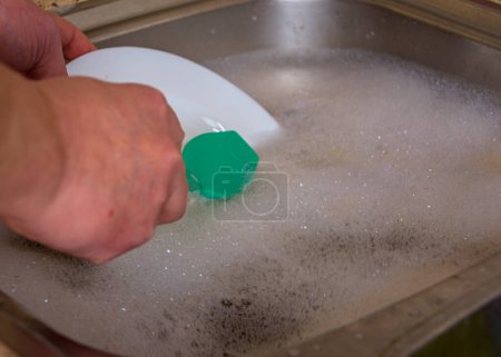 Foto de Primer plano de lavar un plato blanco en un fregadero con suds - Imagen libre de derechos