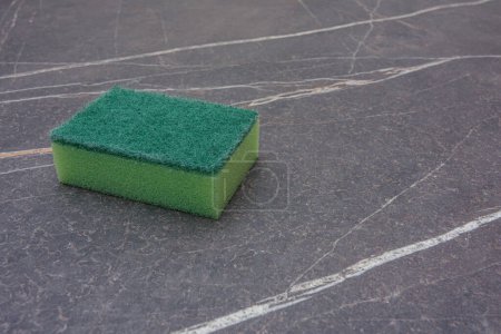 Téléchargez les photos : Une éponge de nettoyage verte sur un plateau en marbre - en image libre de droit