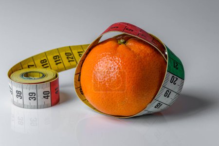 Téléchargez les photos : Mandarin isolé avec ruban à mesurer sur fond blanc, concept santé et alimentation - en image libre de droit