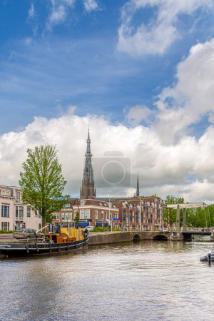 Téléchargez les photos : Leeuwarden, Pays-Bas - 12 juin 2021 : Le clocher de l "église Saint-Boniface s" élève au-dessus des maisons. Vue de l'Oostergrachtswal à Leeuwarden par une journée d'été avec quelques nuages - en image libre de droit