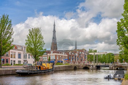Téléchargez les photos : Leeuwarden, Pays-Bas - 12 juin 2021 : Le clocher de l "église Saint-Boniface s" élève au-dessus des maisons. Vue de l'Oostergrachtswal à Leeuwarden par une journée d'été avec quelques nuages - en image libre de droit