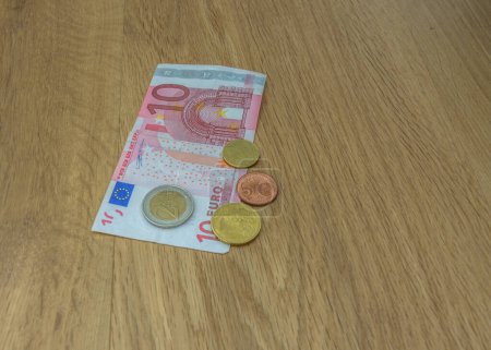 Euro coins and a ten euro bill on a wooden table