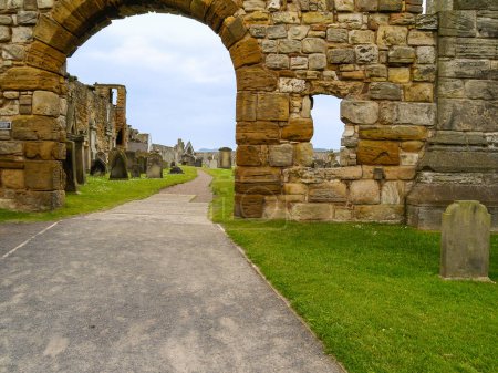 Foto de Camino bajo arco de piedra en la pared perimetral del cementerio en St Andrews Escocia. - Imagen libre de derechos