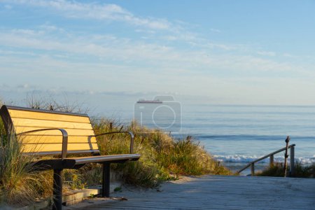 Foto de Pasarela de madera que conduce a través de las dunas al asiento del banco y la playa del océano Papamoa a la luz de la mañana Tauranga Nueva Zelanda. - Imagen libre de derechos