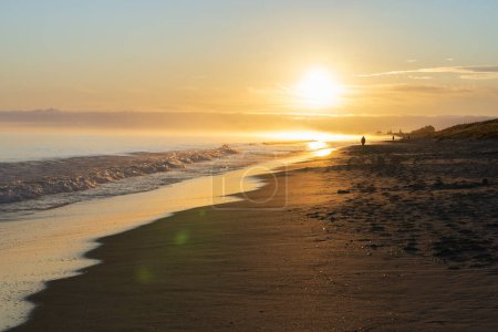 Foto de Playa de Papamoa en el sol de la mañana caminantes de la mañana irreconocibles en silueta. - Imagen libre de derechos