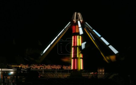 Foto de Carnival attraction spinning illuminated on dark night with bright lights - Imagen libre de derechos
