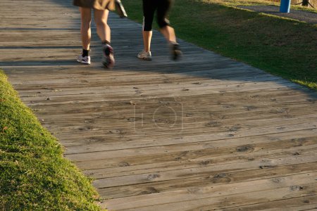 Photo for Mount Maunganui New Zealand - May 2 2010; Editorial-legs only of two people walking along wooden walkway - Royalty Free Image