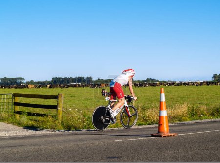 Foto de Tauranga Nueva Zelanda - 8 de enero de 2011; ciclistas concursantes en carretera en Puerto de Tauranga Mitad Iron-man a lo largo de la carretera rural más allá de la granja. - Imagen libre de derechos