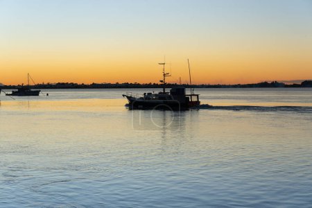 Foto de Barco de pesca comercial saliendo de Tauranga en la luz de la mañana en silueta - Imagen libre de derechos