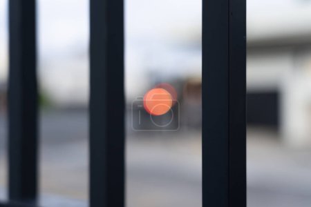 Foto de Luz roja borrosa y desenfocada y paisaje urbano a través de barras verticales de valla de seguridad. - Imagen libre de derechos