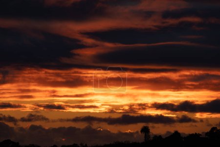 Foto de Intenso amanecer brillante sol dorado iluminando el cielo a través de nubes oscuras - Imagen libre de derechos