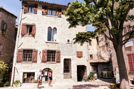 Photo for Saint Paul de Vence, Provence,  France - May 2 2011; Two tourists in ancient street surrounded by old stone buildings - Royalty Free Image