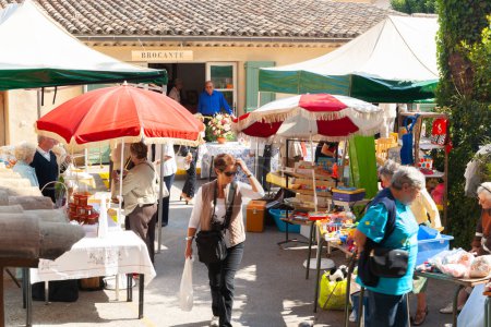 Photo for Saint Paul de Vence, Provence,  France -May 2 2011; Typical weekend flea market with patrons blurred in motion as they lood at offerings - Royalty Free Image