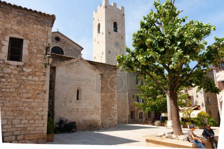 Photo for Saint Paul de Vence, Provence,  France - May 2 2011; Old stone residential building in street in ancient town square with tower and clock - Royalty Free Image