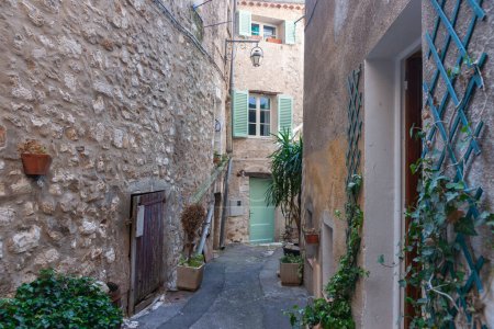 Photo for Narrow alleyway between stone building to door apartment door and window with green shutters in Saint Paul de Vence, Provence,  France. - Royalty Free Image