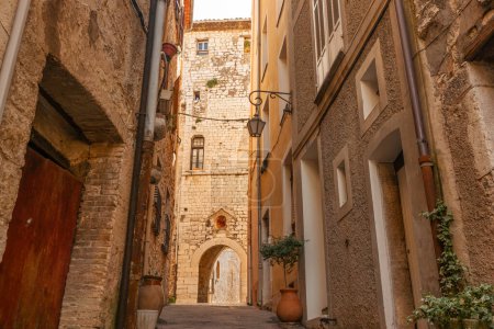 Photo for Sun shines on wall at end of shady high walled old European lane in residential district. Saint Paul de Vence, Provence, France. - Royalty Free Image