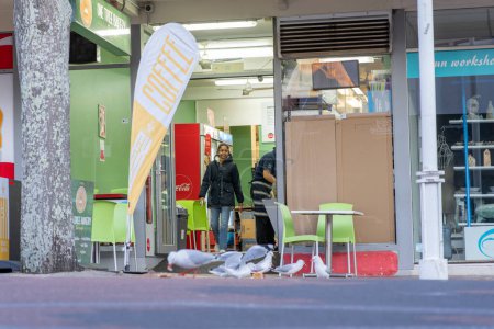 Foto de Tauranga Nueva Zelanda _ 22 de agosto de 2023; entrada urbana de la escena callejera a la cafetería a nivel de calle con gaviotas en el pavimento. - Imagen libre de derechos