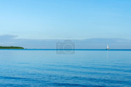 Téléchargez les photos : Petit yacht lointain à voile à l'horizon naviguant vers une petite île de l'océan Pacifique près des Fidji. - en image libre de droit