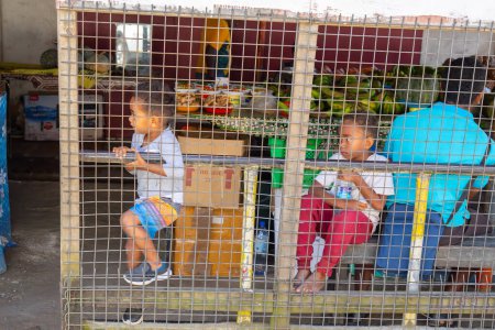 Téléchargez les photos : Sigatoka Fidji - 8 septembre 2023 ; enfants ennuyés qui attendent derrière le marché des parents décrochage derrière la barrière - en image libre de droit