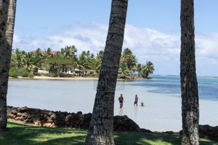 Téléchargez les photos : Yanuca Island Fidji - 6 septembre 2023 ; scène côtière à travers des troncs de palmiers avec des garçons dans des poissons-lance - en image libre de droit