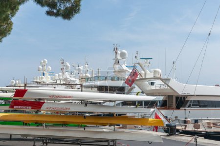 Photo for Monaco May 2 2011;  luxury boats moored beyond rowing skiffs on rack on wharf - Royalty Free Image