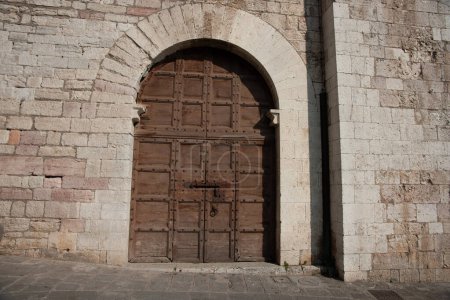 Foto de Antiguo panel de madera envejecida arco-puerta en la pared de piedra en la calle en la histórica ciudad italiana. - Imagen libre de derechos