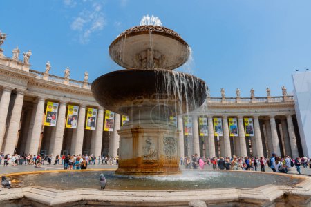 Photo for Rome Italy - May 21 2011; Editorial- St Peter's courtyard and large fountain with crowd of tourists surrounded by famous colonnade with banners of past popes and with statues of saints around top. - Royalty Free Image