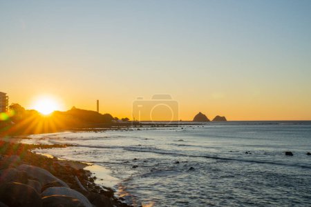 New plymouth waterfront view along coast to setting sun and New Plymouth power station chimney.