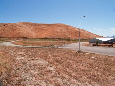 Photo for New industrial land with new road in summer drought colours subdivided and roaded awaiting development of new buildings under blue sky. - Royalty Free Image
