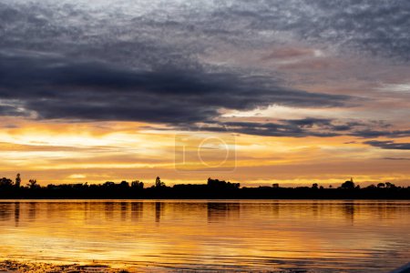 Photo for New day sunrise golden reflection on water with varied cloudy sky across bay. - Royalty Free Image