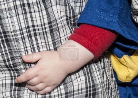 Different fabric and pattern clothing over-lapping close-up with child's hand.