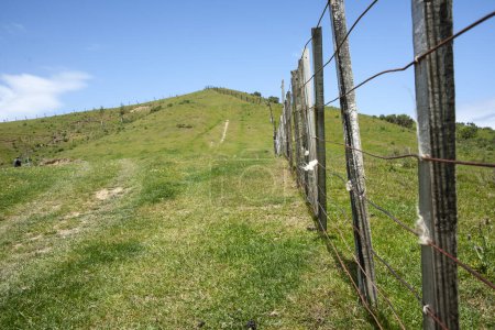 línea de valla que conduce cuesta arriba en la granja hacia el pico y el cielo azul.