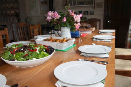 Salat in Schüssel mit Essen und Tischdekoration in traditionellem Bauernhaus.