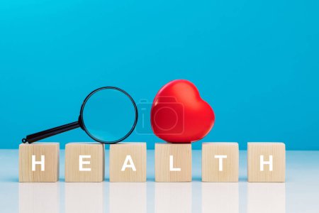 Photo for Red heart and magnifying glass on top of wooden cubes with the word HEALTH on a table in studio - Royalty Free Image