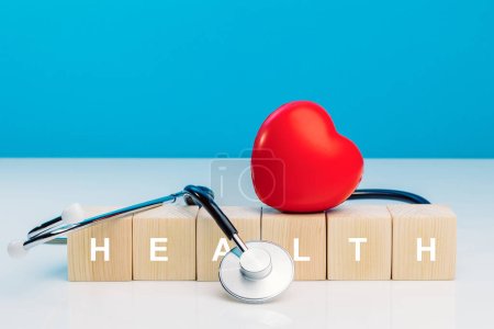 Photo for Diagnosis cardiologist concept. Text health on wooden cube blocks with red heart and stethoscope on blue background. Equipment check heartbeat and pulse of patient - Royalty Free Image