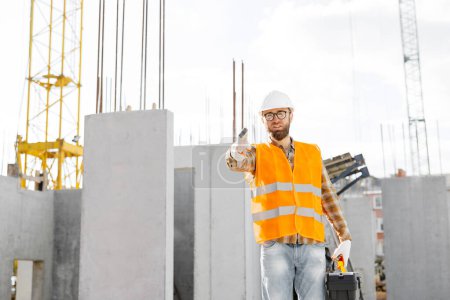Téléchargez les photos : Portrait d'un homme heureux constructeur étirant la main pour poignée de main sur le fond d'un mur de béton dans la maison. - en image libre de droit
