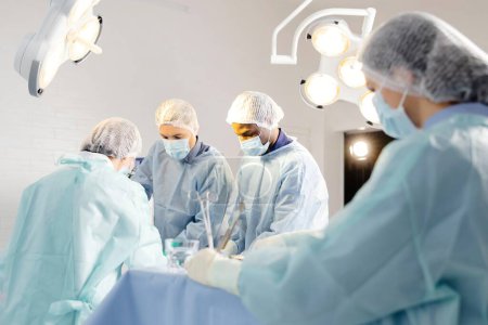 Group of doctors performing surgery in operating room.