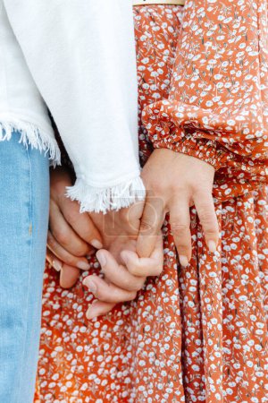 Eine detaillierte Ansicht von zwei Individuen, deren Hände eng aneinander geklammert in einem starken Band, symbolisiert Einheit und Verbundenheit.