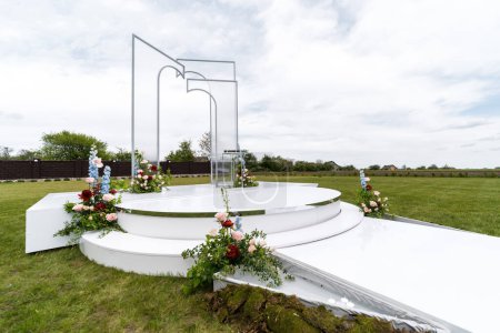 A sizable white sculpture stands prominently in the center of a vibrant green field under the open sky.